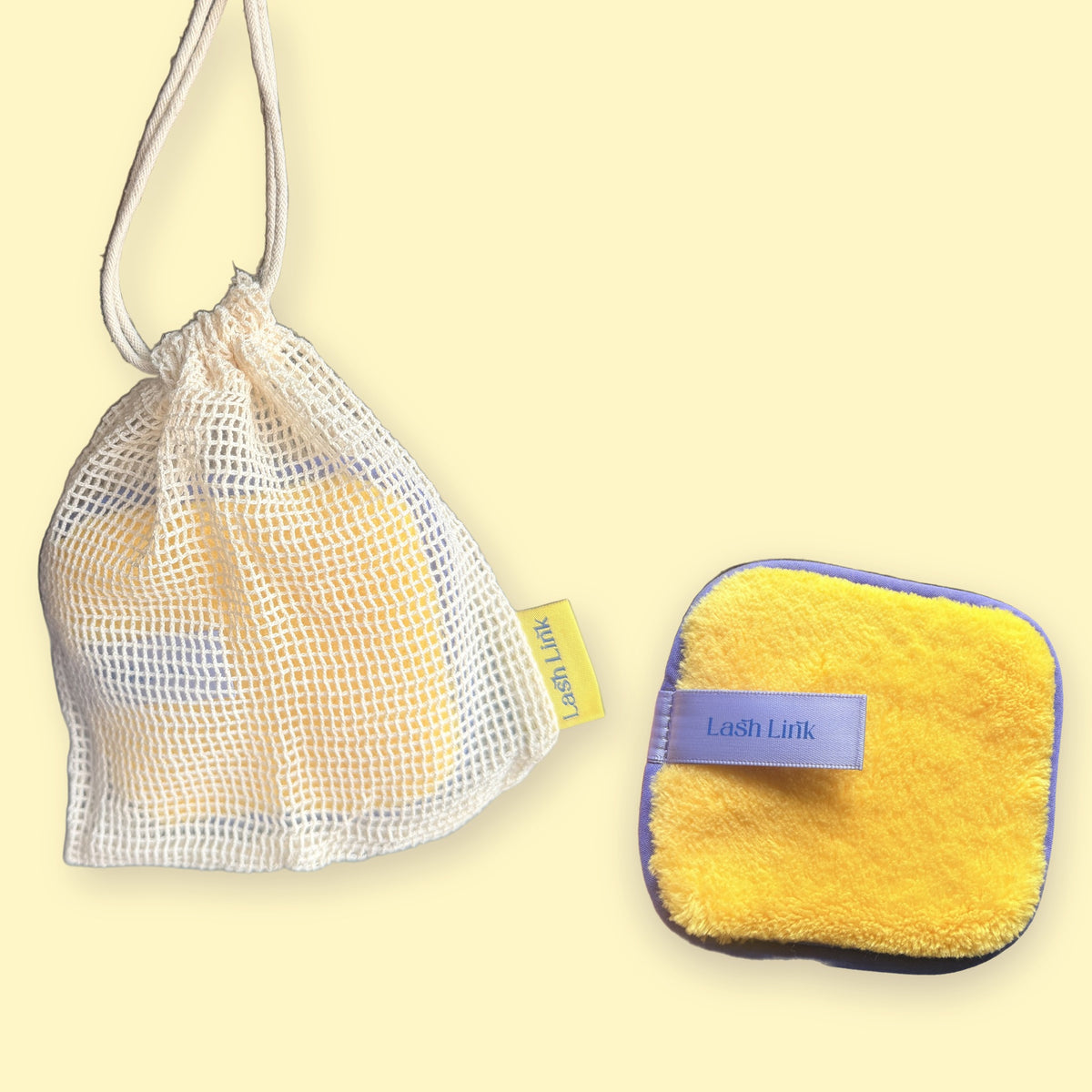 Lash Link Cleansing Sponge next to its cream cotton mesh drawstring bag with a yellow Lash Link tag