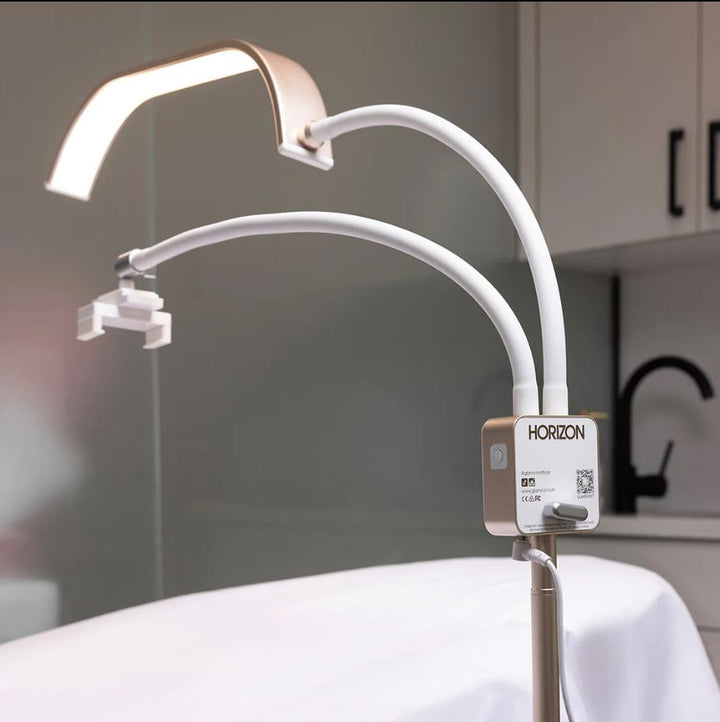A Lash Tribe GLAMCOR Horizon PRO KIT | Light for lashing sits on top of a bed, providing lighting for a lash artist.