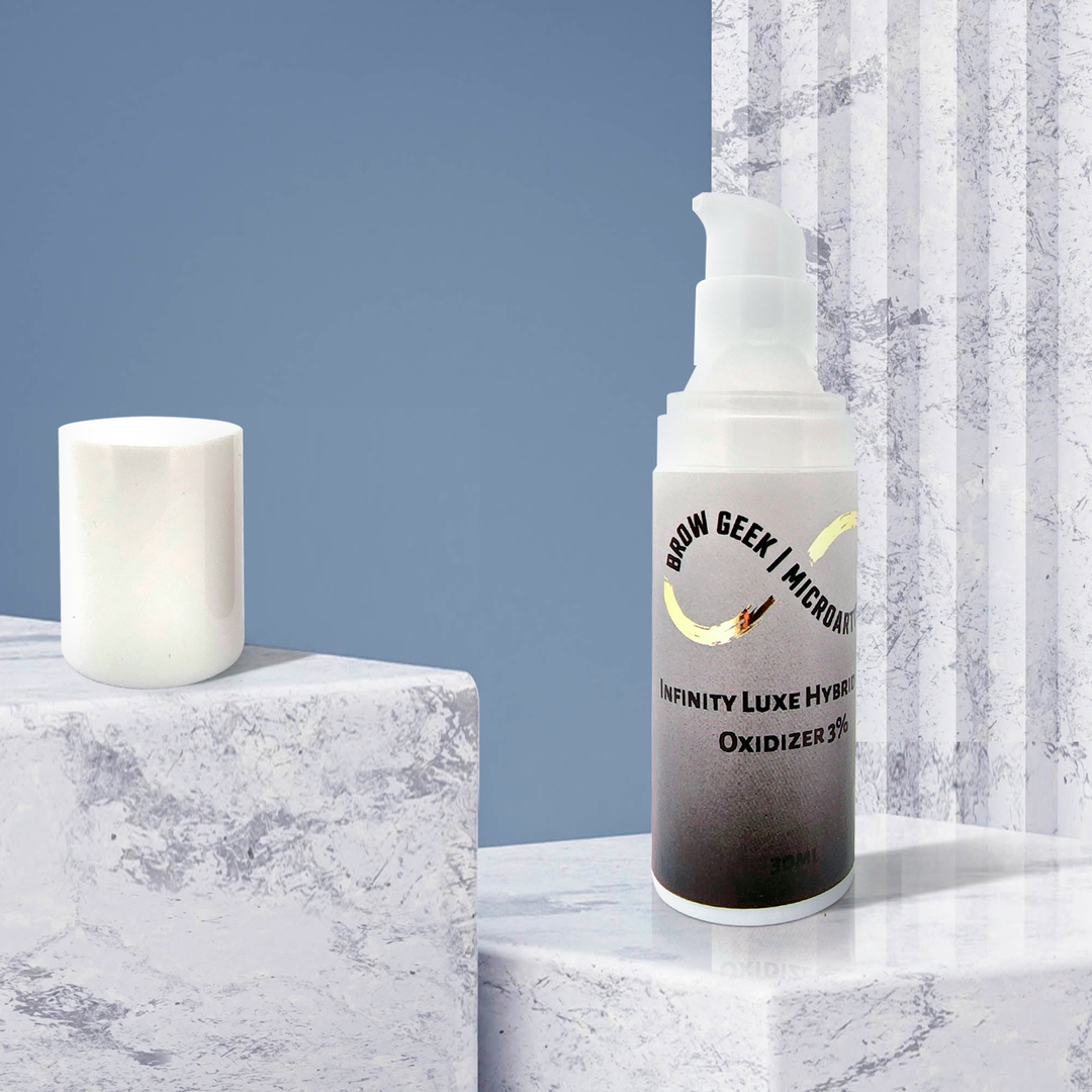 A bottle of INFINITY PUMP DEVELOPER OXIDISER 30ML | Lash Lifting | Brow Tinting Developer by Lash Tribe next to a candle on a marble table.