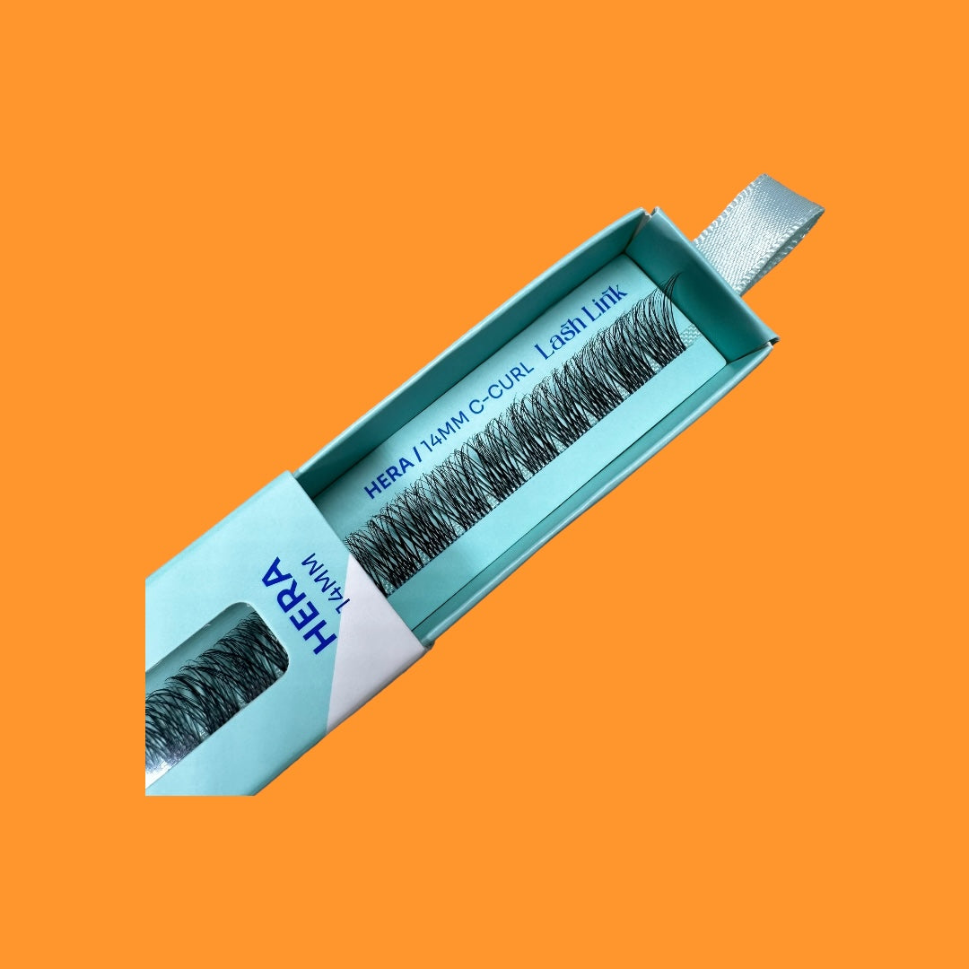 An open teal box of LIGHT VOLUME | HERA | LASH LINK LASH EXTENSIONS RIBBON by Lash Link is shown, displaying the 14mm C-Curl ribbon lash extensions inside against a solid orange background.