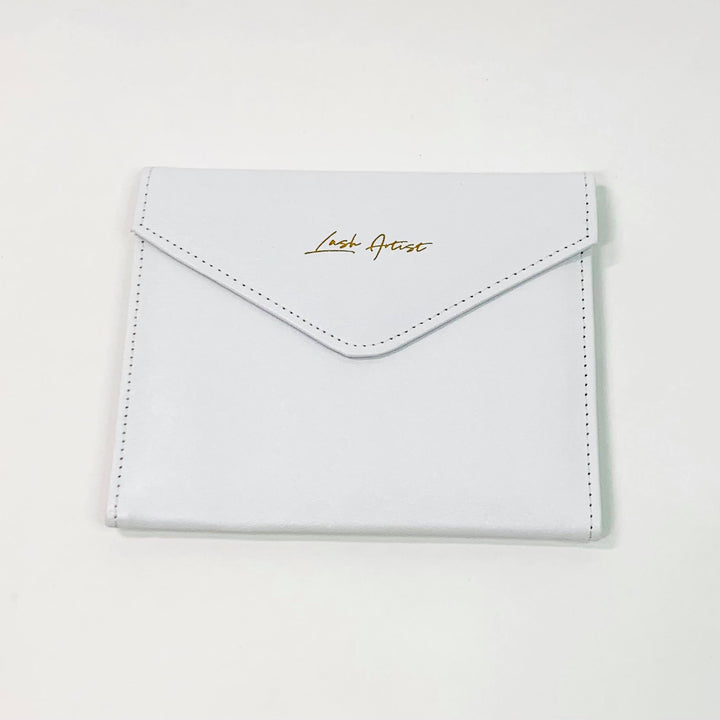 A Lash Tribe Tweezer Envelope with gold lettering on it.