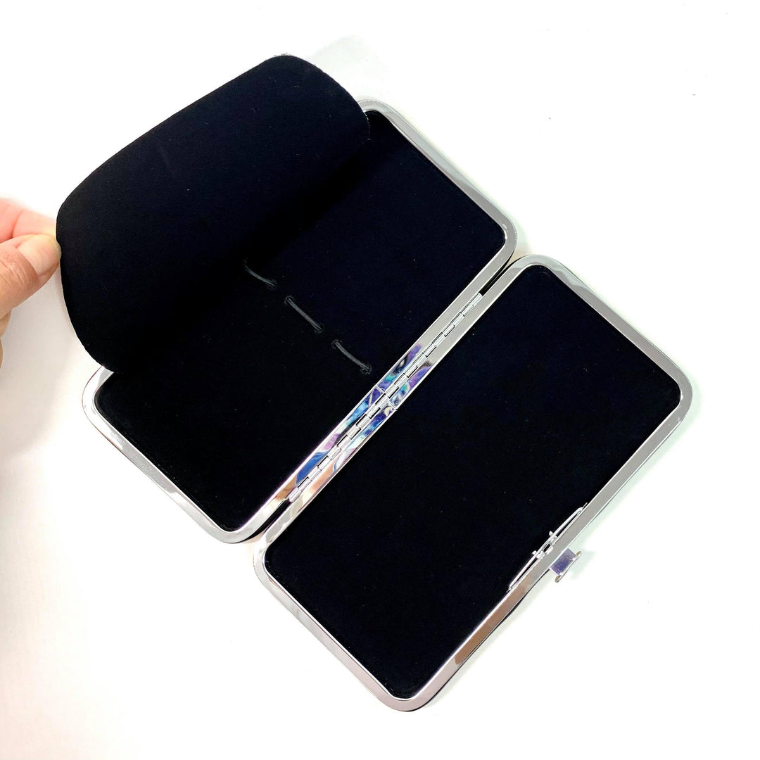 A person holds open a Lash Tribe Gold Magnetic Tweezer Case, which is rectangular, double-sided, and lined with velvet.
