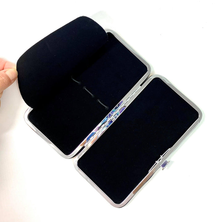 A person holds open a Lash Tribe Gold Magnetic Tweezer Case, which is rectangular, double-sided, and lined with velvet.