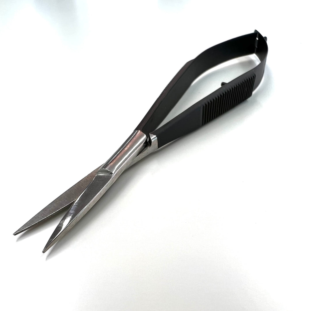 A pair of Lash Tribe Black Spring Scissors made from Japanese stainless steel with sharp, pointed blades lying on a white surface.