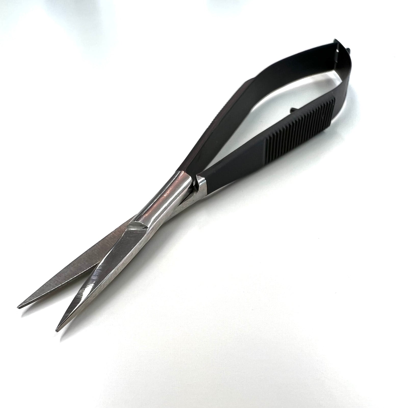 A pair of Lash Tribe Black Spring Scissors made from Japanese stainless steel with sharp, pointed blades lying on a white surface.